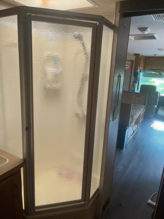 Compact RV rental interior featuring a frosted glass shower and spacious living area. Perfect for travel!. Fleetwood Flair 31A 2005