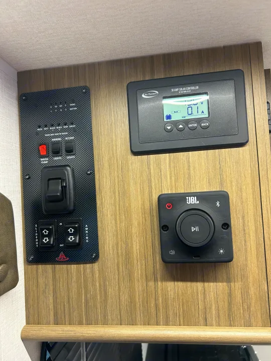 RV rental control hub with panels for tank/battery levels, Go Power! solar, slide-out, awning, and JBL audio.. Forest River RV Wildwood 31KQBTSX 2025