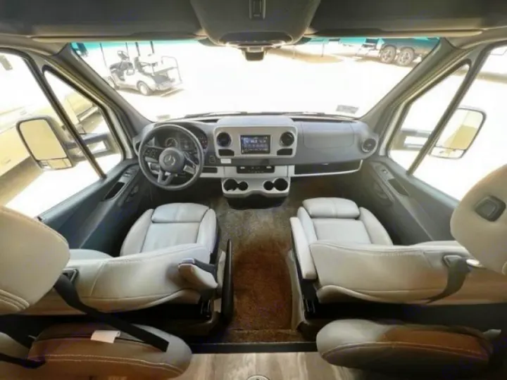 RV rental's spacious front cabin: Mercedes-Benz dashboard, steering wheel, and plush captain's seats.. Thor Quantum 2022