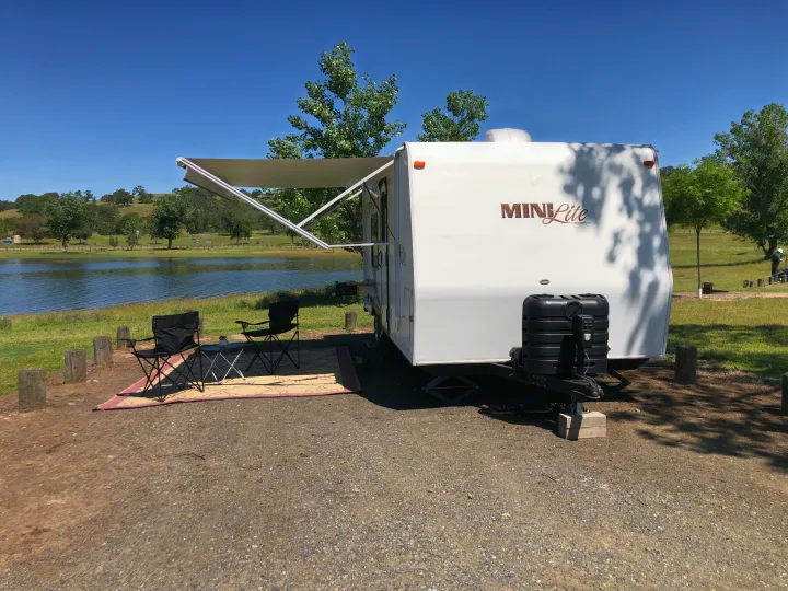 Relax by the lake in an RV rental. This perfect campsite features an extended awning, chairs, and table.. Forest River Rockwood Mini Lite 2012