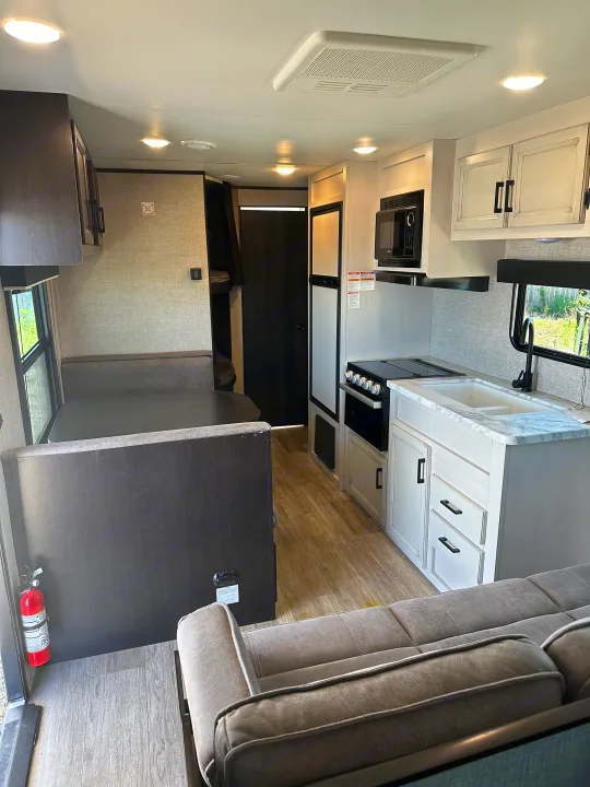 Inside a clean RV rental: kitchen with white cabinets, dining booth, comfy sofa, and bunk beds. Perfect travel trailer.. Jayco Jay Flight 2022