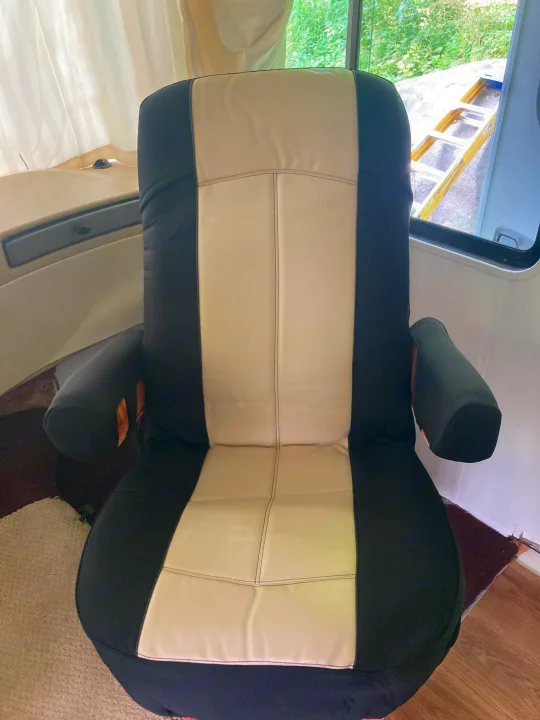 A comfortable, two-tone black and light beige captain's chair is central in this RV rental interior, offering outdoor views.. Monaco Monarch SE 2006