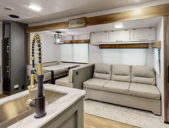 Experience comfort in this RV rental! Features a modern kitchen with a sink, dining booth, and a cozy sofa for travel.. Heartland RVs Eddie Bauer BHS 34 2024