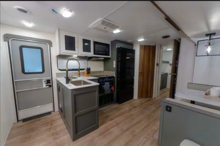 Modern RV rental interior featuring a full kitchen with sink, stove, fridge, and a cozy dinette. Perfect for your next adventure.. Heartland RVs Eddie Bauer BHS 34 2024