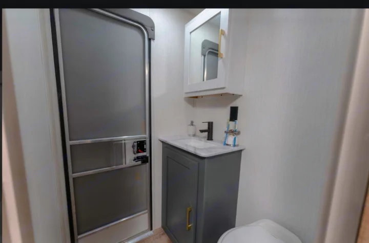 Step inside this RV rental's modern bathroom, featuring a gray shower, vanity with sink, medicine cabinet, and toilet.. Heartland RVs Eddie Bauer BHS 34 2024