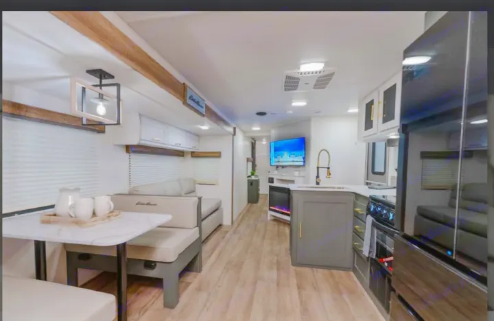 Spacious RV rental interior with a cozy dining area, well-equipped kitchen, and a living space featuring a TV and fireplace.. Heartland RVs Eddie Bauer BHS 34 2024