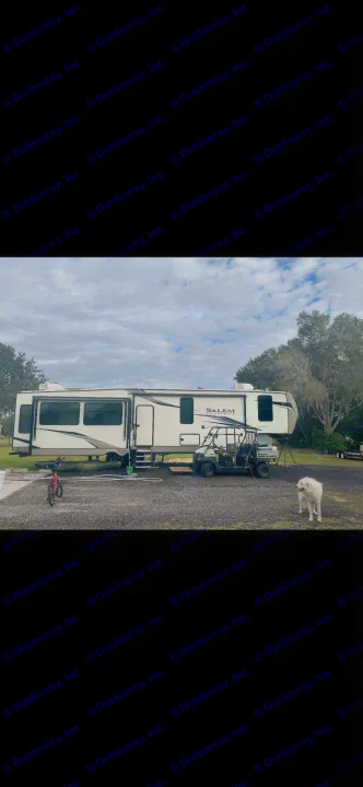 This RV rental, a Salem Hemisphere fifth-wheel, is parked at a campsite with a UTV, kayak, and a white dog.. Forest River Hemisphere 2022