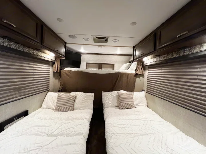 RV rental interior with two lower beds & an upper bunk, offering comfortable family sleeping arrangements.. Gulf Stream Conquest 2022