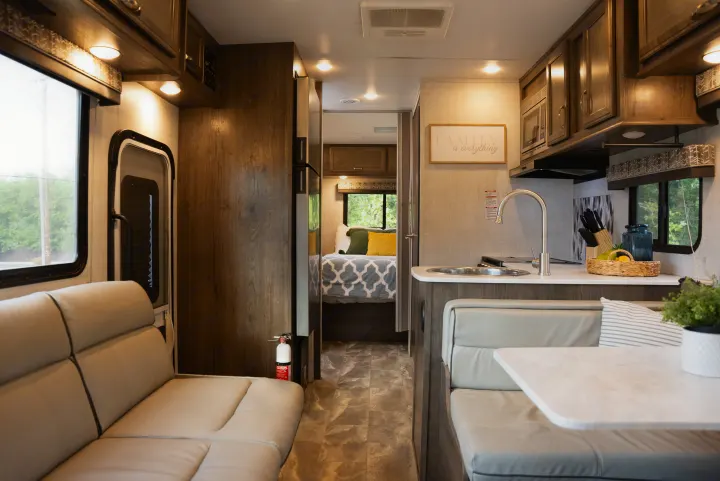 An RV rental interior features a kitchen with sink & microwave, dining nook, and a bedroom visible in the back.. Gulf Stream Conquest 2022