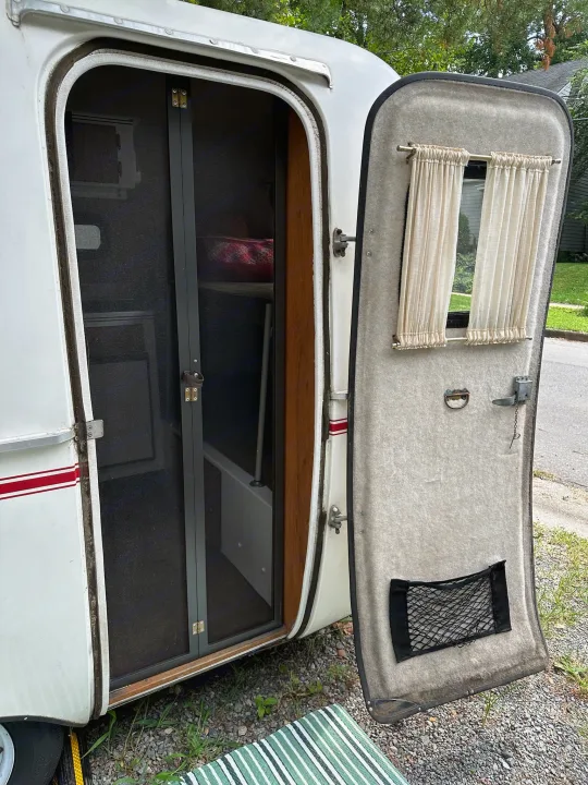 Step into this vintage RV rental! Open door reveals a screen, cozy interior bunk, and door with window & storage.. Scamp Scamp Trailer 2011