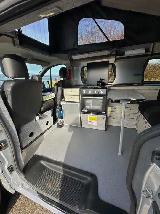 Well-equipped RV rental interior: kitchen with stove, oven, fridge; pull-out table; comfy seating; pop-top roof.. Renault Other 2023