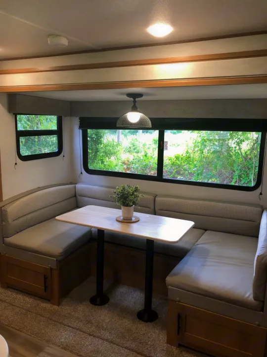 RV rental dinette featuring U-shaped booth seating, a light table, and bright windows with lush outdoor views.. Forest River Prime Time Avenger 24BHS 2023