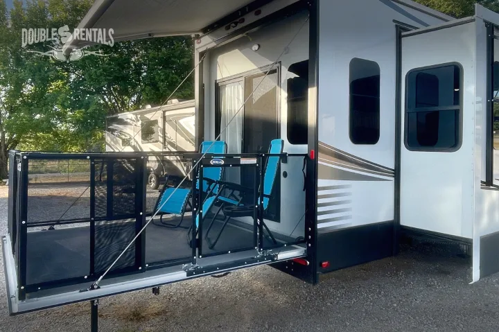 RV rental with a deployed mesh patio, blue chairs, and an awning for a comfortable outdoor setup.. KZ Durango Gold 2022