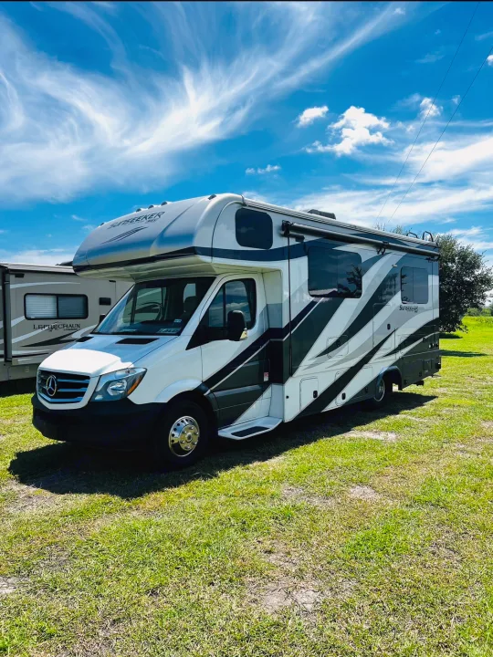 Explore with this Sunseeker Class C RV rental, a white and gray motorhome parked on green grass under a blue sky.. Forest River Sunseeker MBS 2019