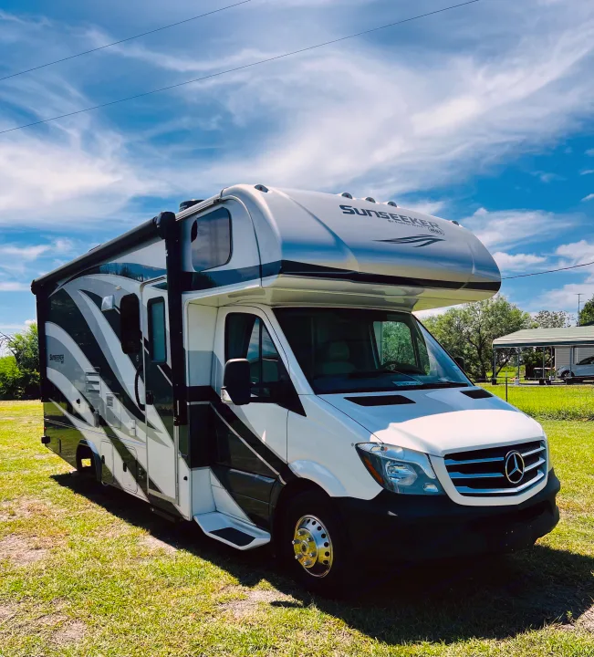 Explore in comfort with this white and black Sunseeker RV rental, parked on grass under a bright blue sky.. Forest River Sunseeker MBS 2019