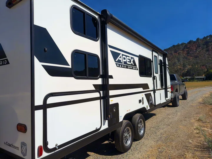 APEX NANO OFF GRID travel trailer (like an rv rental) hooked to a truck on a rural road, ready for off-grid camping.. Coachmen Apex Nano 2024