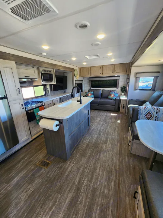 Explore this modern RV rental interior! Features a full kitchen, comfortable living area, and stylish wood-look floors.. Forest River Aurora Aurora 2024