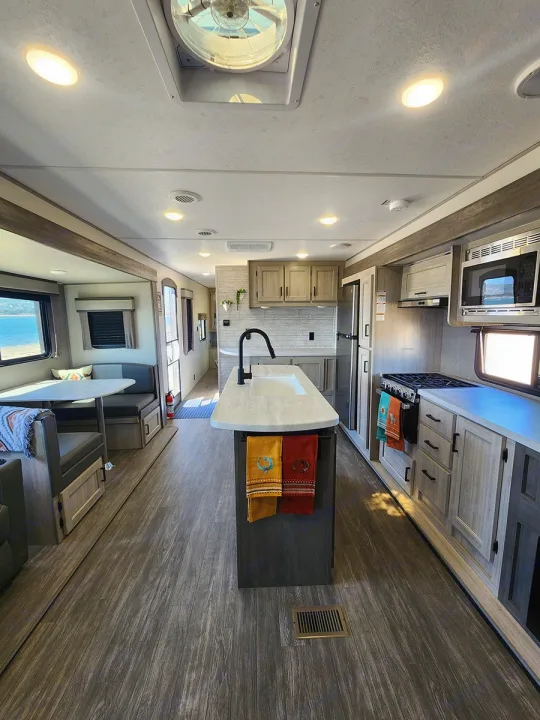 Spacious RV rental interior with a modern kitchen island, dining area, and bright lighting, offering comfort for travel.. Forest River Aurora Aurora 2024