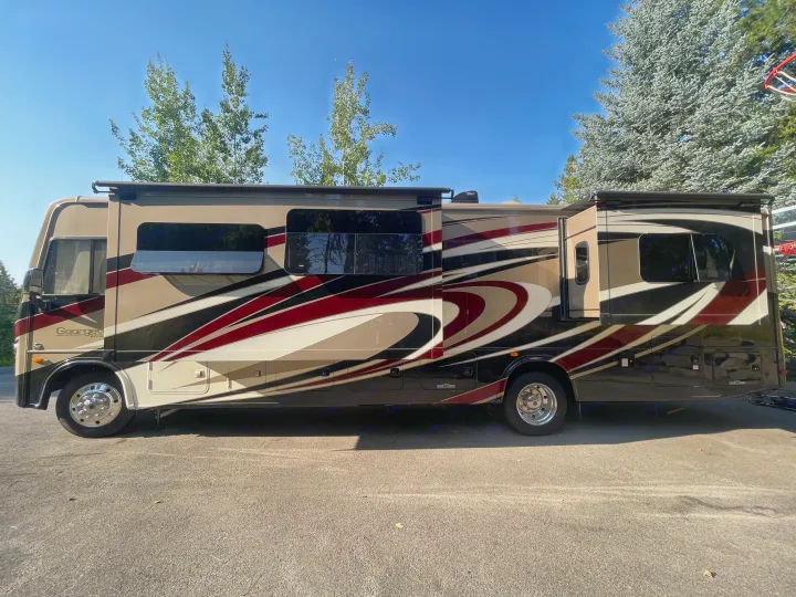 This large, multi-colored Georgetown Class A motorhome, perfect for an rv rental, is seen parked with slide-outs extended.. Georgetown GT5 2019