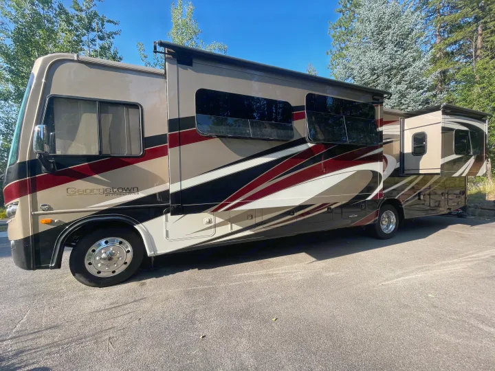 Spacious Georgetown RV rental, featuring an extended slide-out and sleek design, parked on asphalt with trees visible.. Georgetown GT5 2019