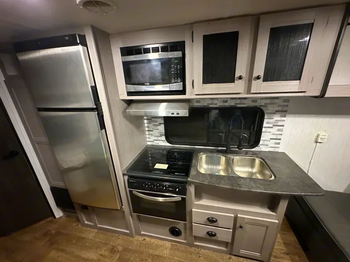 RV rental kitchen: full view of compact cooking and prep area with fridge, microwave, and sink.. Heartland RVs Trail Runner 2022