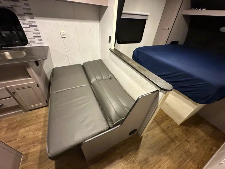 RV rental interior: practical kitchen, versatile bench seating, and a comfortable rear bedroom with a mounted TV.. Heartland RVs Trail Runner 2022
