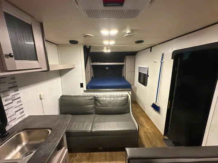 Bright RV rental interior. Includes kitchen with sink, sofa, bed, and ceiling AC/lights for comfort.. Heartland RVs Trail Runner 2022