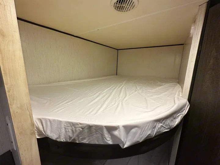 Compact RV rental bunk bed with fresh white sheets, ready for a restful sleep.. Heartland RVs Trail Runner 2022