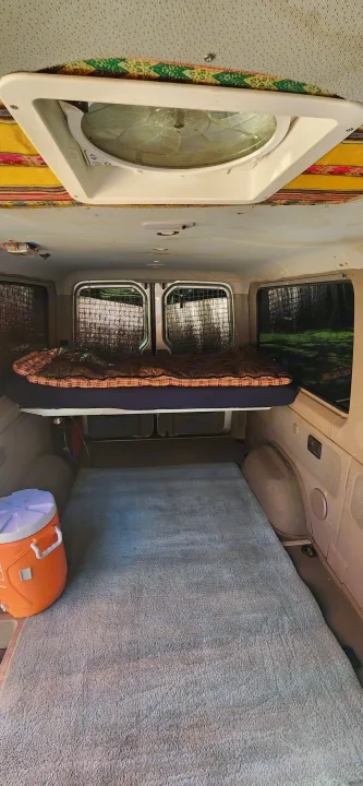 Inside an RV rental: a cozy elevated bed, ample floor space with a rug, and a ceiling fan for comfort.. Dodge Sprinter Van 2007