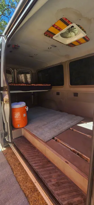 Explore this RV rental van's cozy interior: elevated bed, Home Depot cooler, rug, and decorative ceiling fan.. Dodge Sprinter Van 2007