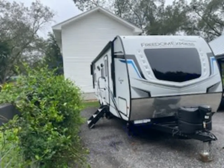 This Freedom Express travel trailer RV rental is parked by a white house, ready for your next adventure.. Coachmen 257 BHS 2021