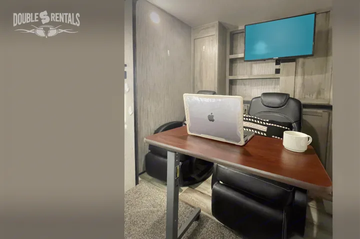 Modern RV rental interior with a cozy workspace featuring a laptop, desk, and TV. Perfect for on-the-go productivity.. KZ Durango Gold 2022