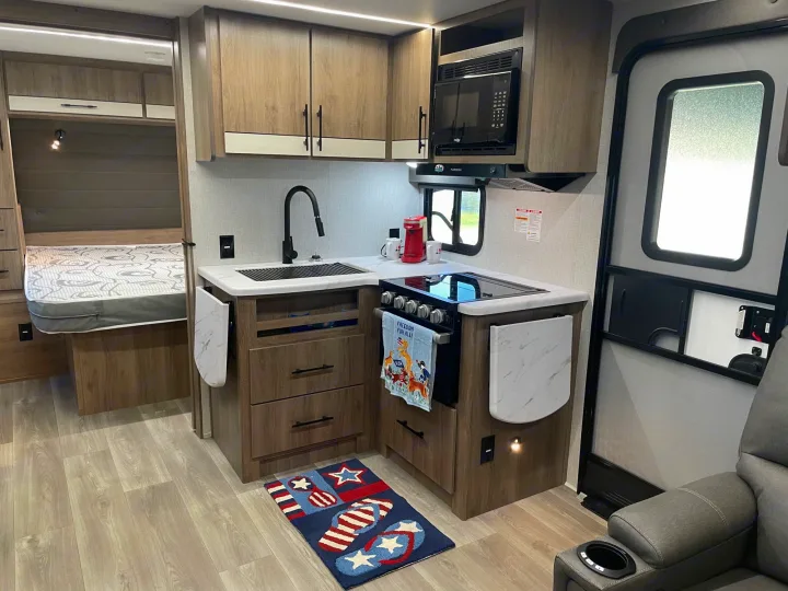 Inside this modern rv rental: a well-equipped kitchen, comfortable bed, and compact living area are ready for adventure.. Grand Design Imagine XLS 2024
