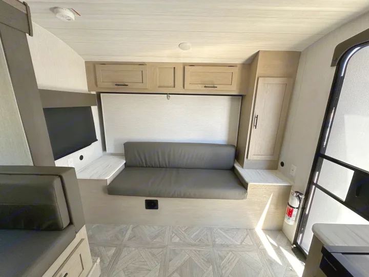 Spacious RV rental interior with comfortable seating, a wall-mounted TV, overhead storage, and light wood-look flooring.. Forest River Wildwood Platinum 2024