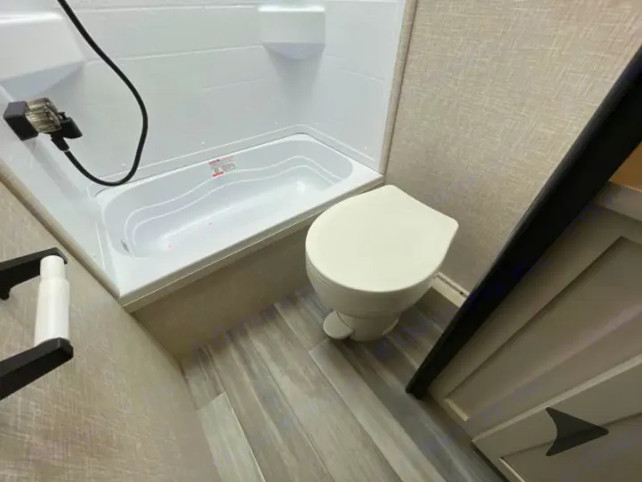 Experience convenience in this RV rental bathroom, featuring a white shower/tub combo, toilet, and stylish grey flooring.. Jayco Jay Flight 2024