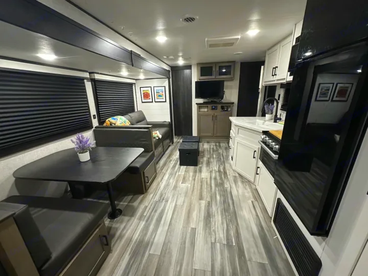 Modern RV rental interior: spacious living, dining booth, and kitchen with black, white, and grey accents.. Jayco Jay Flight 2024