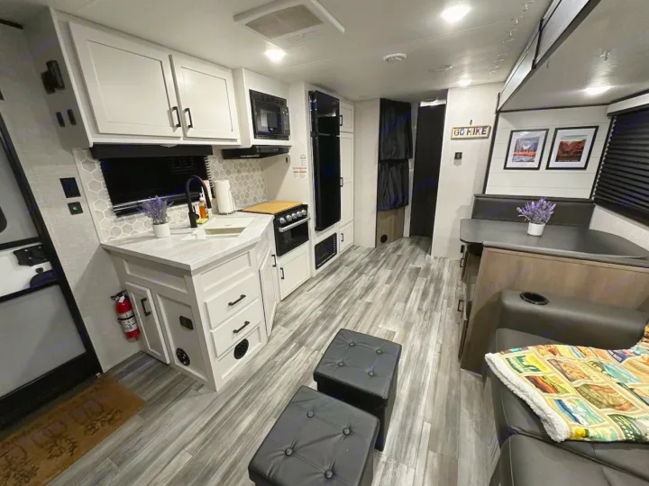 Spacious modern RV rental interior features a white kitchen, dining booth, and living area with black furniture.. Jayco Jay Flight 2024