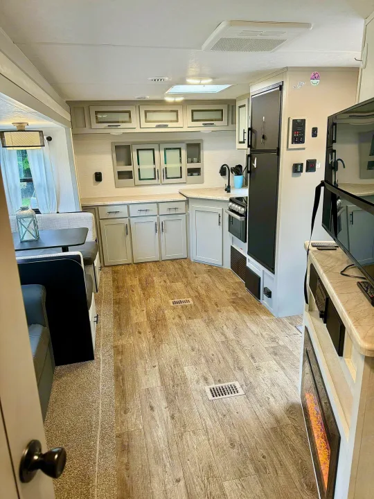 Spacious RV rental interior featuring a modern kitchen, dining booth, and living area with a cozy fireplace.. Forest River Vibe 2021