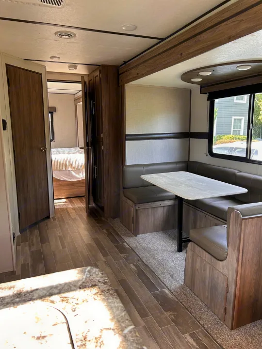 Explore this RV rental's inviting interior: U-shaped dinette, comfortable seating, and a glimpse into the cozy bedroom area.. Crossroads RV Zinger 2021