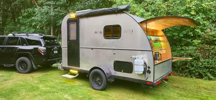 A stylish teardrop trailer with an illuminated outdoor kitchen, ideal for an RV rental and cozy camping adventures.. Bend Teardrop Tall Boy 2023