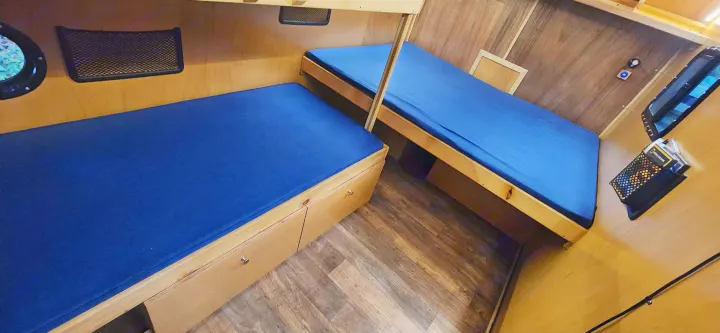 Cozy RV rental interior with two compact bunk beds featuring blue mattresses, wooden paneling, and built-in storage.. Bend Teardrop Tall Boy 2023
