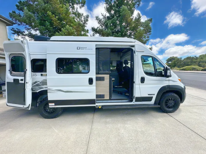 Modern white Winnebago camper van with open doors, perfect for an RV rental adventure or exploring national parks.. Winnebago Solis 2025
