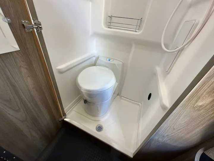 RV rental: Compact wet bath with toilet, shower, drain, and small shelf.. Winnebago Solis 2025