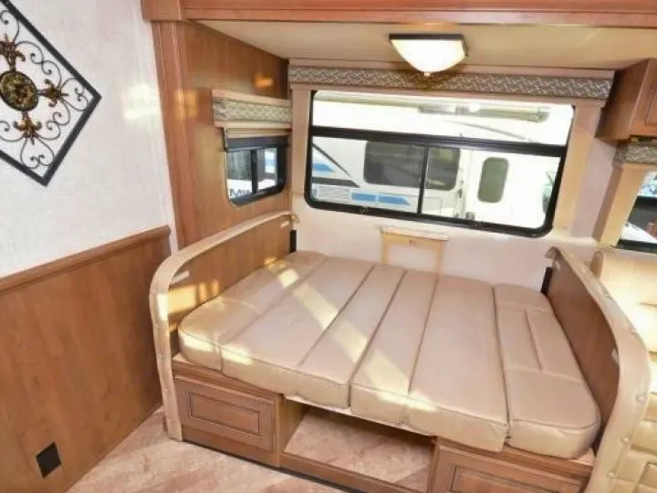 RV rental with a light-colored, convertible bed/couch against wood paneling and windows. A cozy, compact travel space.. Georgetown GT5 2019