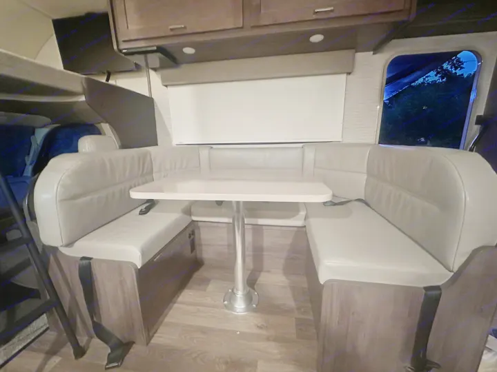 An rv rental dinette with cozy U-shaped seating, a white table, and wood-look flooring.. Winnebago Minnie Winnie 2022