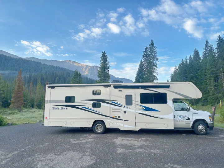 Minnie Winnie rv rental parked in a scenic mountain setting, surrounded by forests and blue skies. Perfect for nature travel.. Winnebago Minnie Winnie 2022
