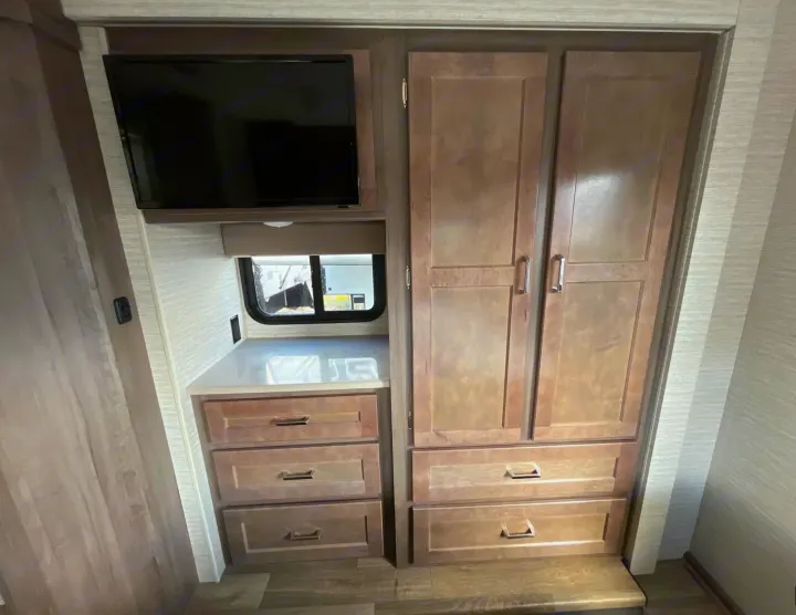 Inside this **rv rental**: a wall-mounted TV, ample storage with built-in wardrobe and drawers, plus a window.. Winnebago Minnie Winnie 2022