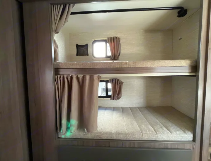 RV rental bunk beds: A cozy sleeping area with stacked beds, mattresses, and windows.. Winnebago Minnie Winnie 2022