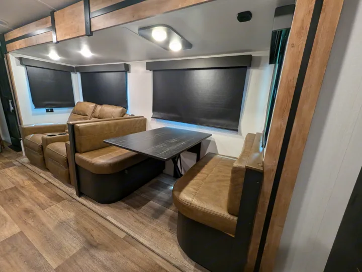 Spacious RV rental interior with brown leather recliners, a dining booth, and wood-look floors, offering comfort.. Keystone RV Outback 2022