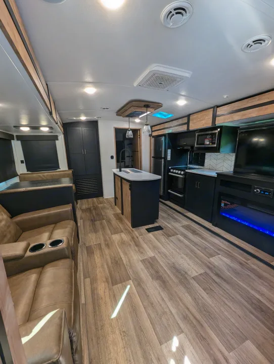 Modern RV rental interior: a spacious living room, full kitchen with an island, and wood-look floors. Ready for adventures!. Keystone RV Outback 2022